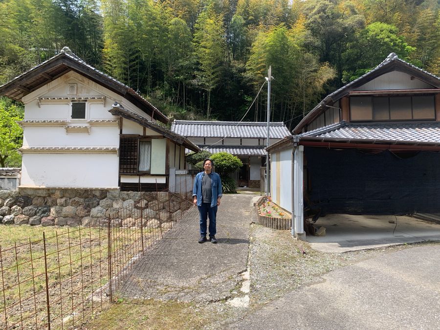 思い出深い祖母の家の前に立つトモさん（今年４月、日高村宮ノ谷）