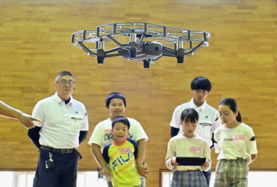 建設会社職員の説明を受けつつ小型ドローンを飛ばす児童（土佐清水市下川口）