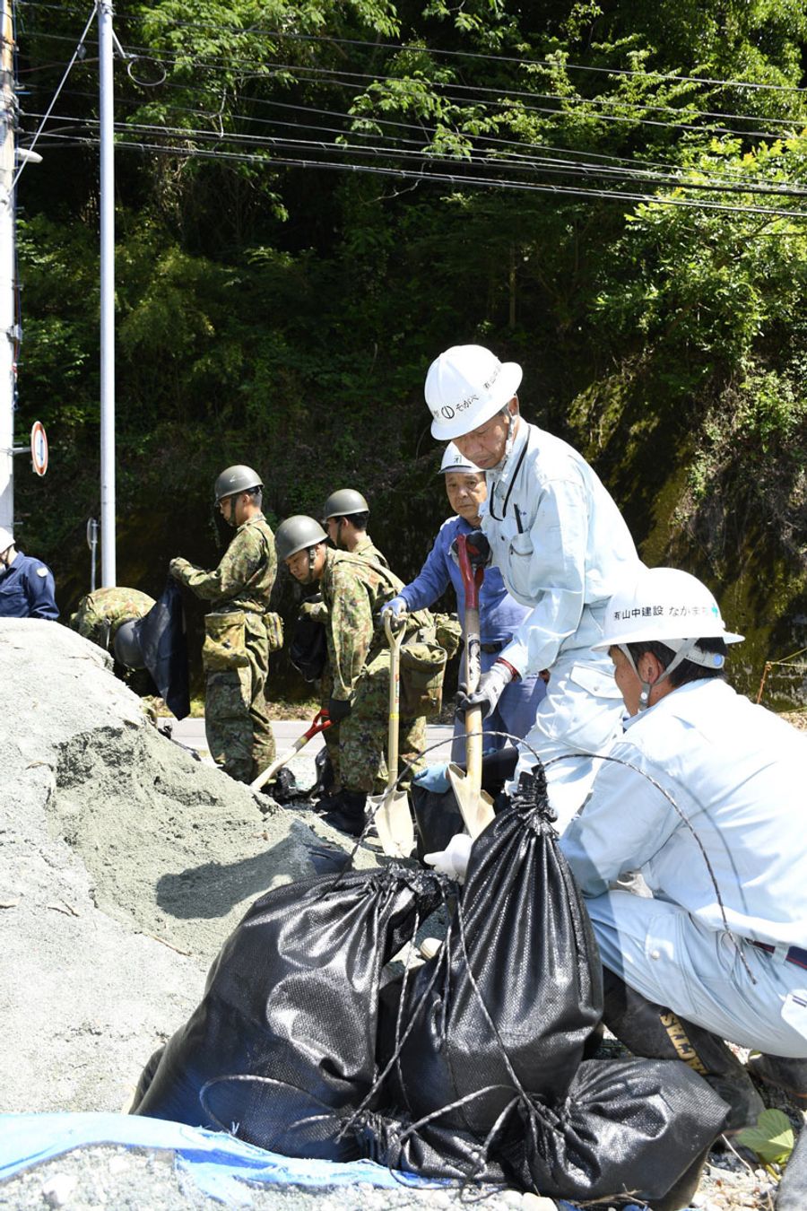 土砂の侵入を防ぐ土のう作りに汗を流す参加者（大川村小松）