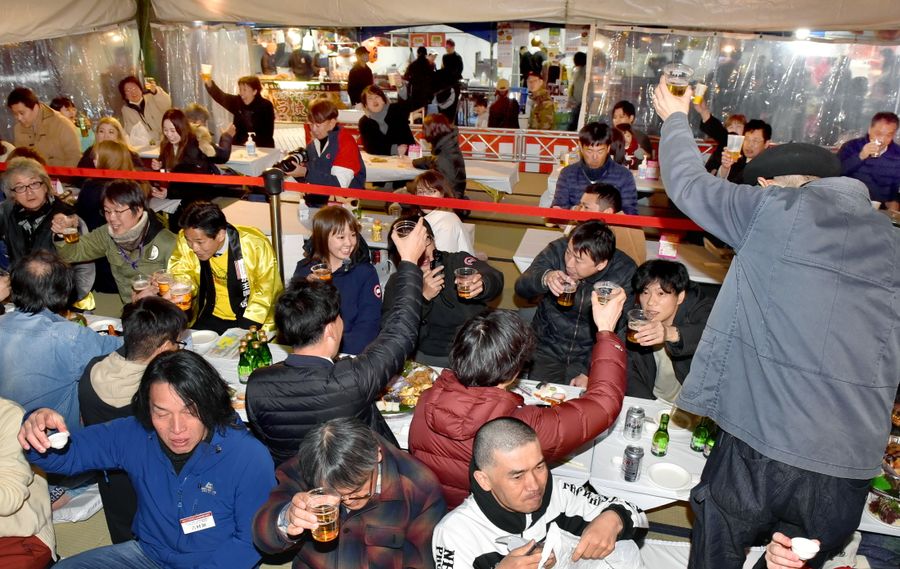 土佐の「おきゃく」２０２４で酒を酌み交わす来場者。経済波及効果は初めて１０億円を超えた（３月、高知市の中央公園）