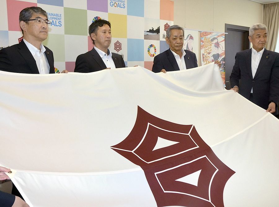 高知市旗を手にする、左から桑名龍吾高知市長、四銀野球部の亀岡洋介監督、橋谷正人部長、板垣政史副部長(高知市役所)