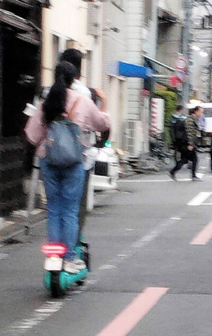 ２人乗りで走る電動キックボード（下京区）＝読者提供