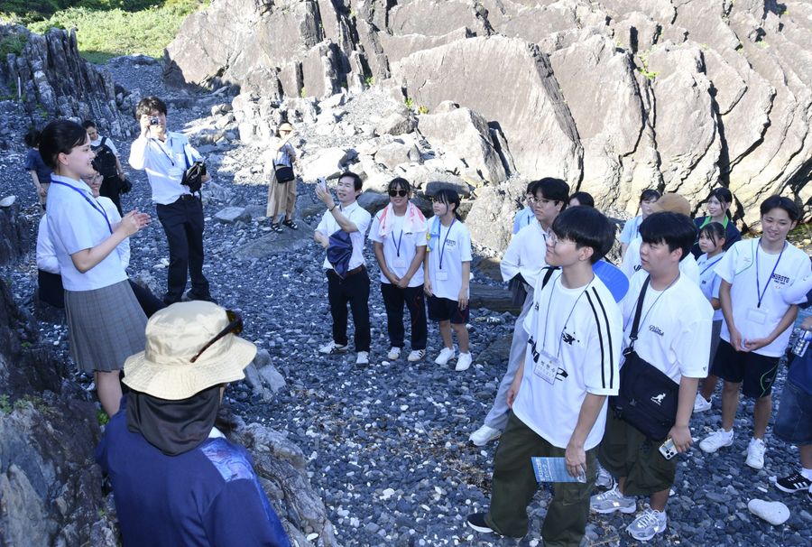 室戸高生（左端）のガイドで室戸岬を見て回る韓国の生徒ら（室戸市）