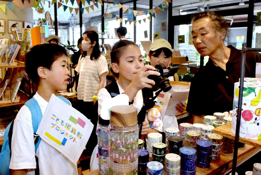 カメラマンの助言を受けて写真を撮る子どもたち（高知市帯屋町１丁目の「ペーパーメッセージ　おびやまち店」）