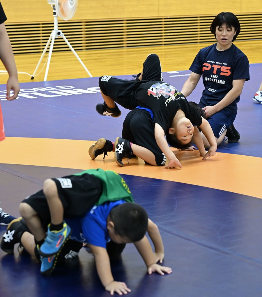 五輪金メダリストの小原日登美さん（右奥）からレスリングの指導を受ける参加者＝宿毛市山奈町芳奈の市総合運動公園