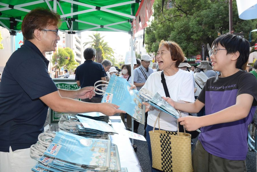 「新聞ばっぐ」を笑顔で受け取る来場者(高知市追手筋1丁目)