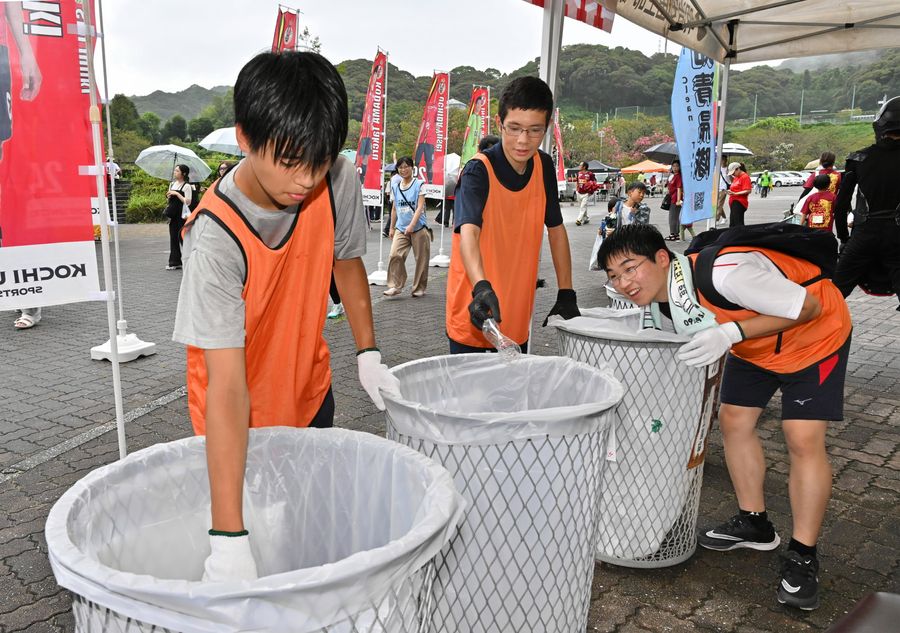 自らが設置したごみステーションで分別を行う山本稜平さん=中央=ら高知清掃隊のメンバー(春野陸上競技場=新田祐也撮影)