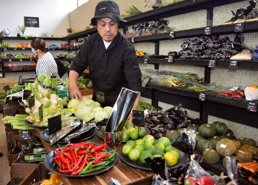 野菜を並べる内田佳久さん。おしゃれでおいしそうに見せる陳列もこだわりだ（高知市南川添の「やさいとくだもの　LIMELAND」）