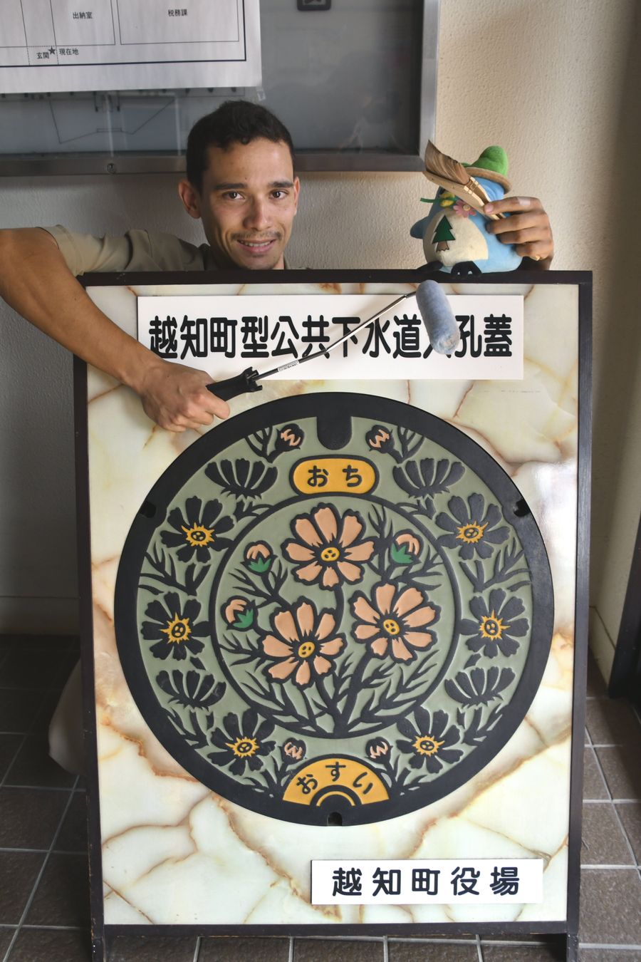 描き写したマンホールの絵柄と、道具を持つリバさん(越知町役場)