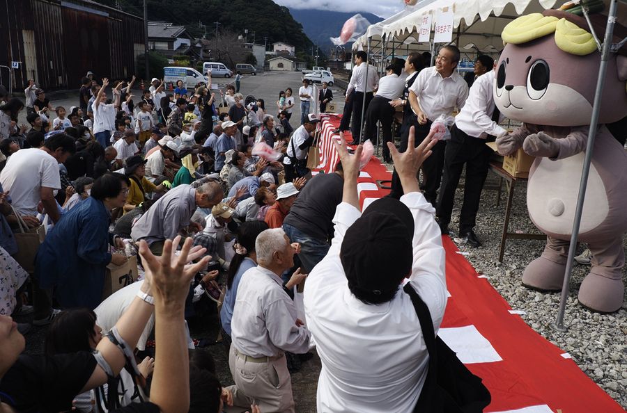 餅投げで市制７０周年を祝うしんじょう君ら（須崎市のＪＲ須崎駅前）