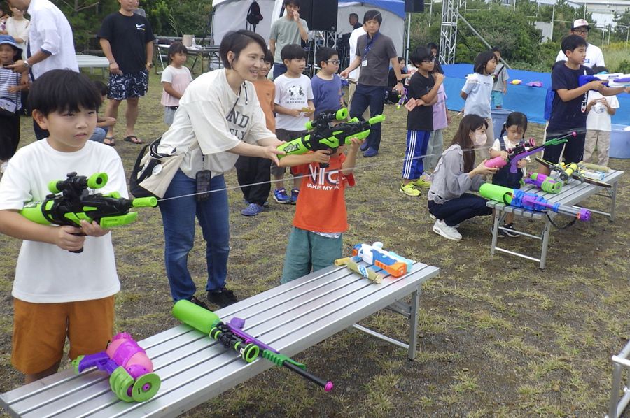 深層水を使った水鉄砲の的当てを楽しむ親子ら（室戸市の高岡漁港ふれあい公園）