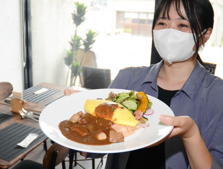 チーズデミグラスオムライスを掲げる筆者（高知市の「ビストロカフェエルフ」）