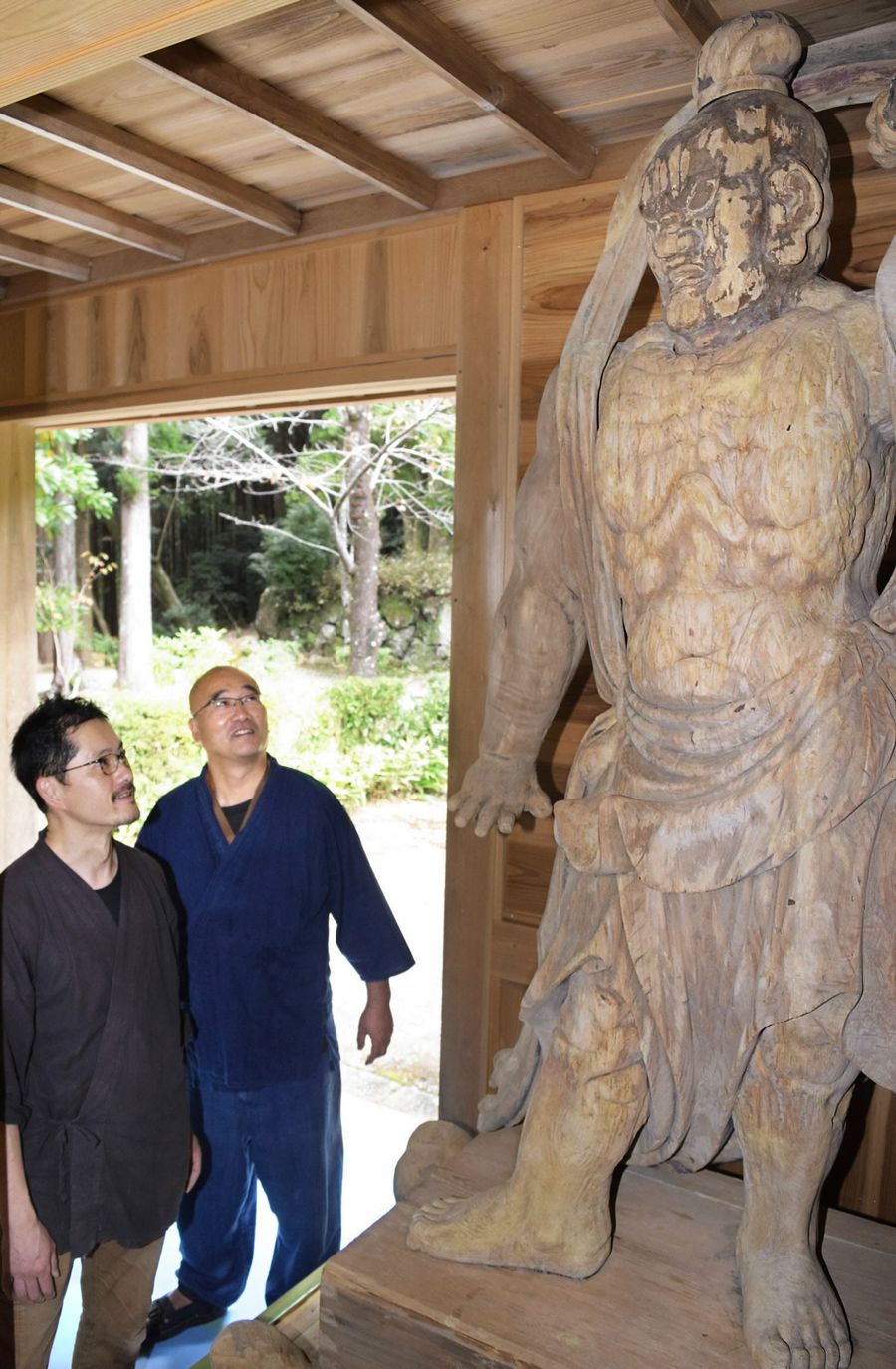 170年ぶりに解体修復を終え、長谷寺に戻ってきた仁王像。仏師の吉田安成さん=手前左と、竹井玄要住職が笑顔で見上げた(写真はいずれも香南市夜須町羽尾)
