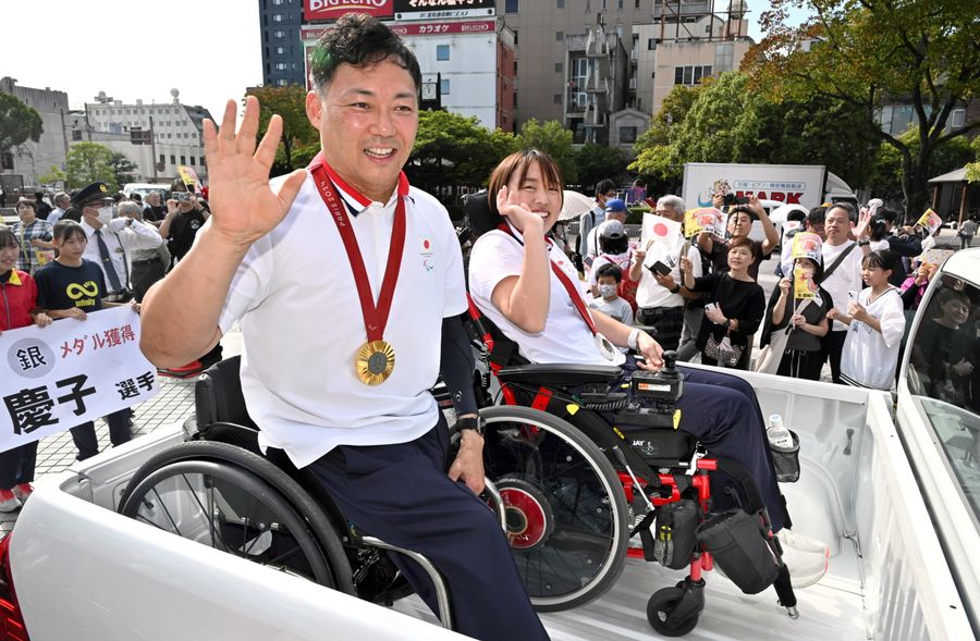 沿道からの声援に笑顔で手を振る池透暢=手前、鬼谷慶子両選手(高知帯屋町1丁目=新田祐也撮影)