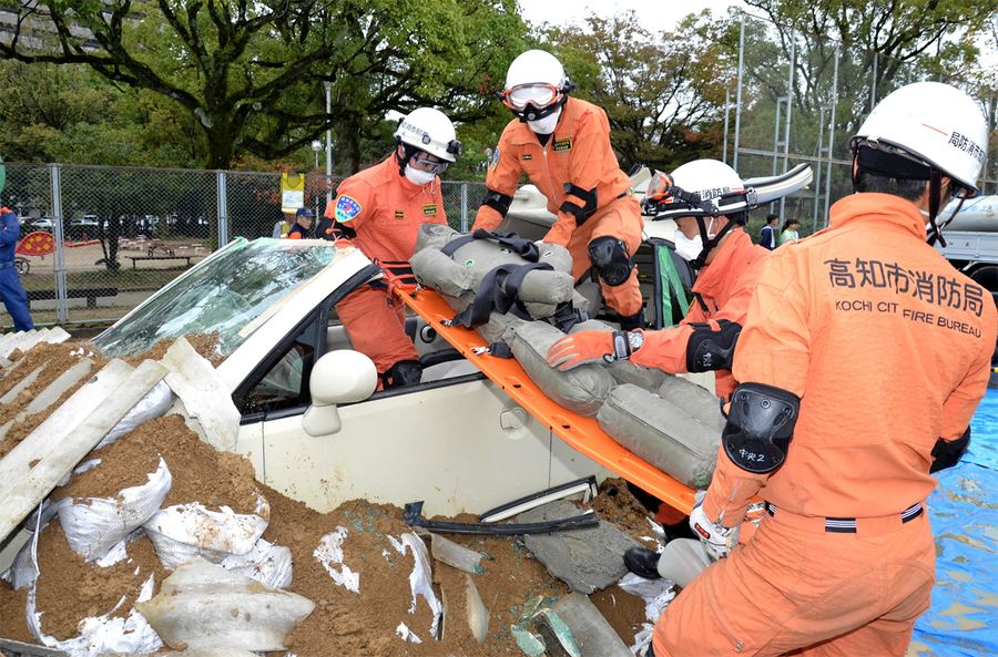 土砂に埋もれた車から、人を模した人形を運び出す消防隊員（高知市の城西公園）