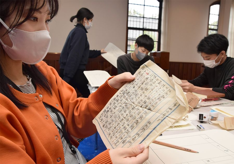 被災史料の目録づくりへ内容を解読する学生たち(石川県金沢市の県立歴史博物館)