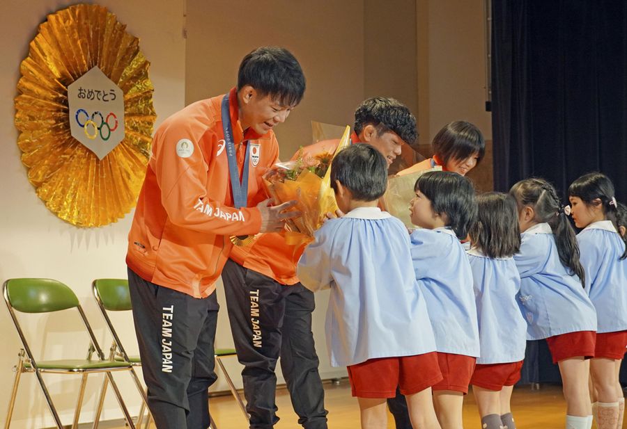 埼玉県吉川市の吉川ムサシノ幼稚園の園児から花束を受け取るパリ五輪レスリング金メダリストの（左から）樋口黎選手、清岡幸大郎選手、桜井つぐみ選手＝１３日午後