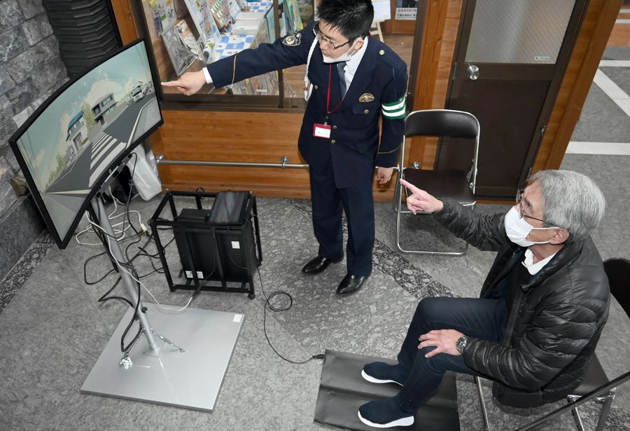 歩行者シミュレーターで車に注意しながら足を動かし横断する参加者ら(高知市の県警本部)