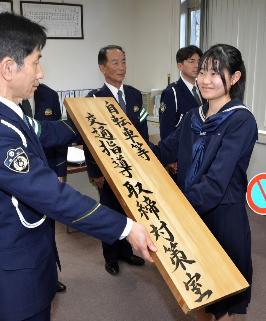 県警に看板を手渡す有光さん（高知市丸ノ内２丁目の県警本部）