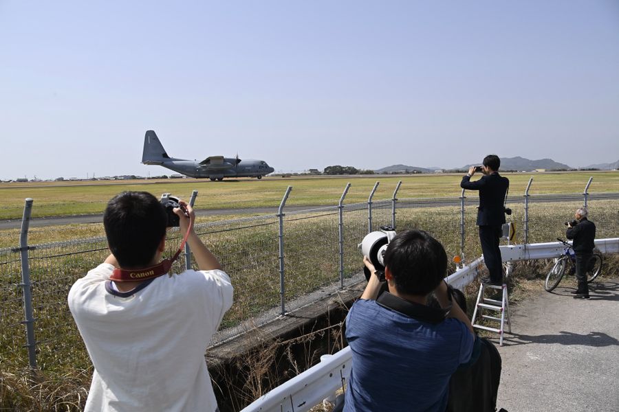 離陸体制に入った米軍の輸送機を撮影する人たち。輸送機は、３０分ほどで空港を後にした（午前１１時２０分ごろ）