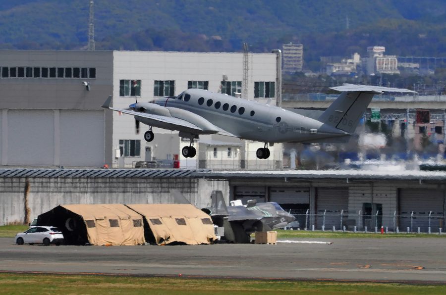 エンジンが取り外されたままの米軍戦闘機＝下＝と離陸する輸送機（３０日午前１０時２０分ごろ、高知龍馬空港）