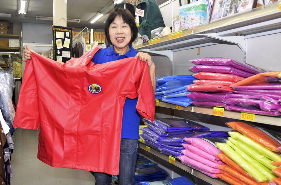 漁師用かっぱを手にする草木原美由紀さん。お気に入りは赤だ（写真はいずれも宿毛市宿毛のワークショップ　クサキハラ）