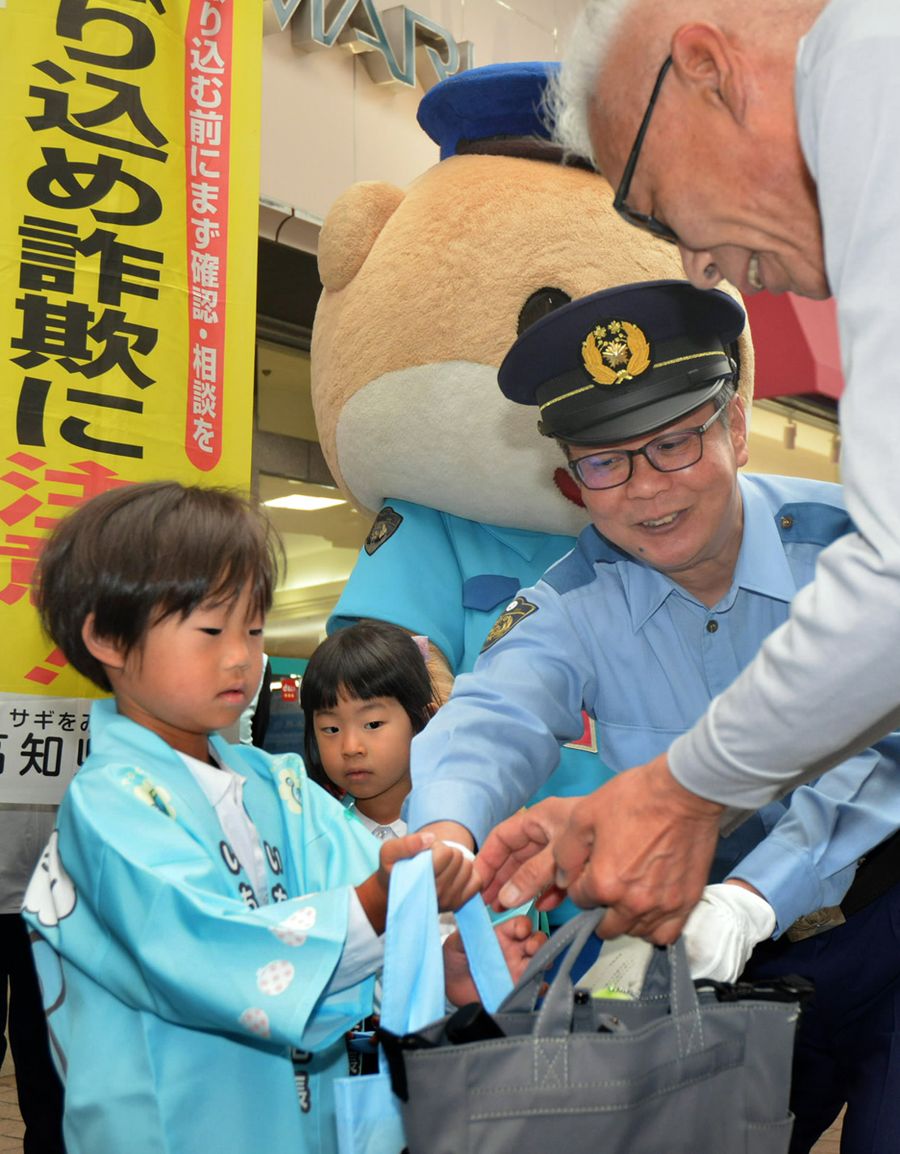 お菓子などが入った袋を手渡し、特殊詐欺への注意を呼びかける園児(高知市帯屋町1丁目)