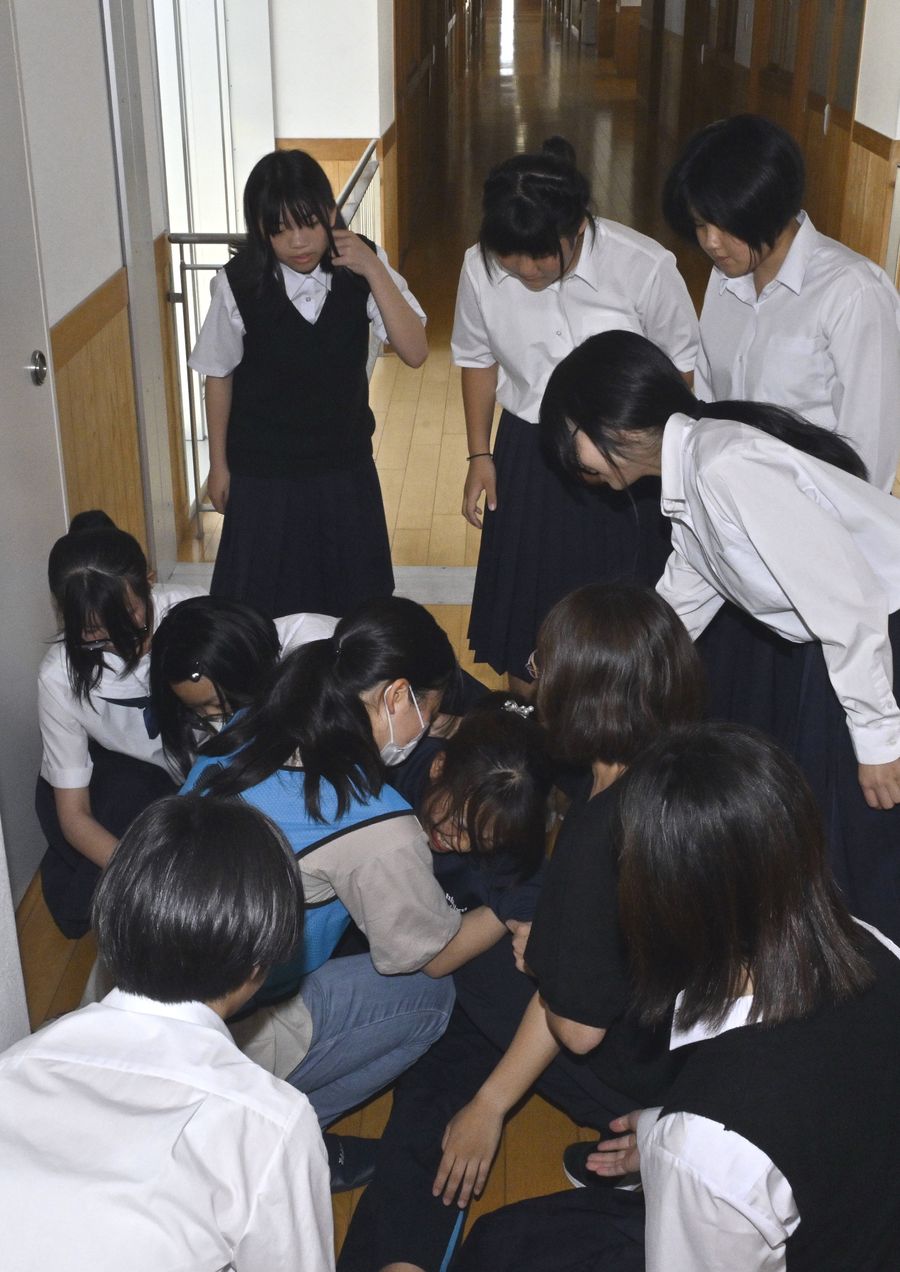 廊下でうずくまる中学生役の大学生に「大丈夫だよ、そばにいるから」などと声がけする清水中学校の生徒と教員（土佐清水市清水ケ丘の同校）