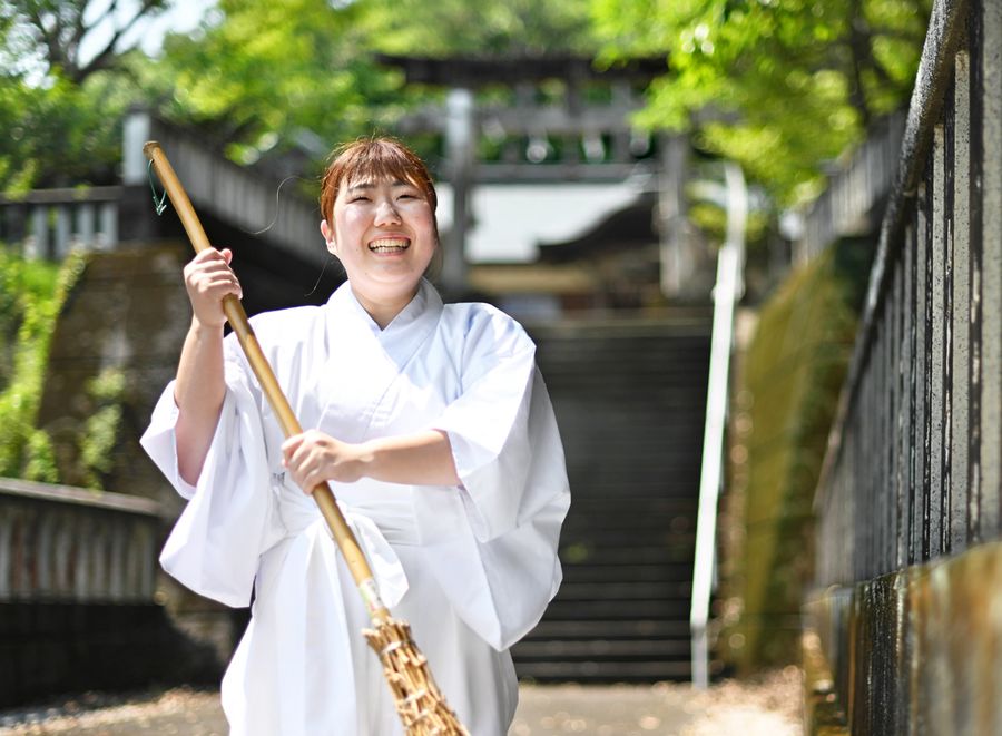 境内の掃除をしながら笑顔で話す小松友紀子さん（室戸市室津の室津八幡宮）