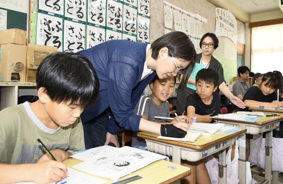 宮部由佳さん（左から２人目）の手ほどきで４こま漫画を描く子どもたち＝写真はいずれも土佐市蓮池の蓮池小学校