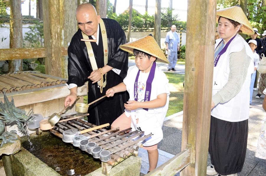 住職から、ちょうずで手を清める作法を教わる親子（南国市の国分寺）