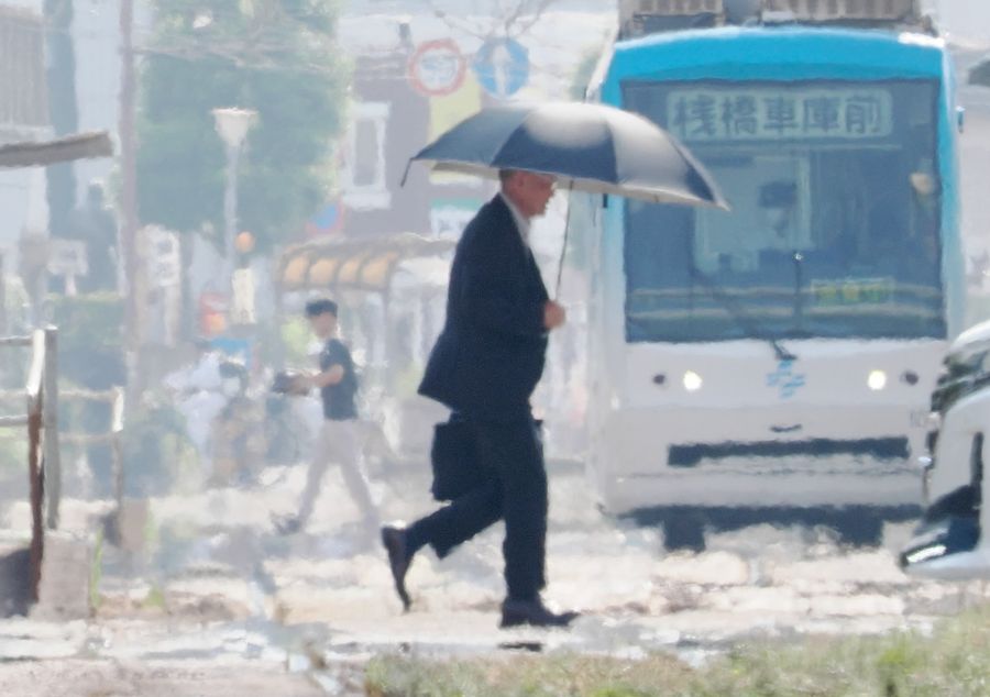 猛暑日に日傘を差して歩く男性(7月7日撮影、高知市本町3丁目)