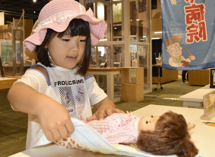 腕が壊れた人形を受け取った女の子。タオルで優しく包んで抱きしめた（高知市追手筋２丁目の高知みらい科学館）