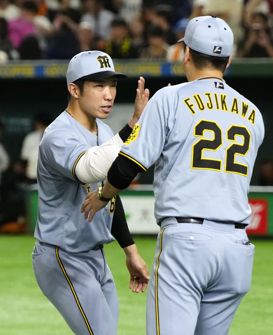 40試合連続無失点のプロ野球真意録を樹立し、藤川球児監督とタッチを交わす石井大智投手=左(東京ドーム)