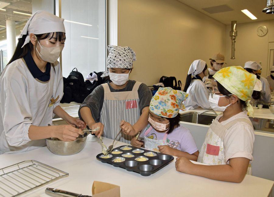 真剣な表情で料理に取り組む生徒と子どもたち(四万十市右山五月町の市総合文化センター「しまんとぴあ」)