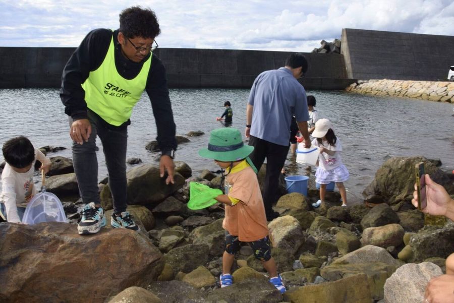 磯で子どもたちに生き物を見せる漁師たち（安芸市伊尾木）