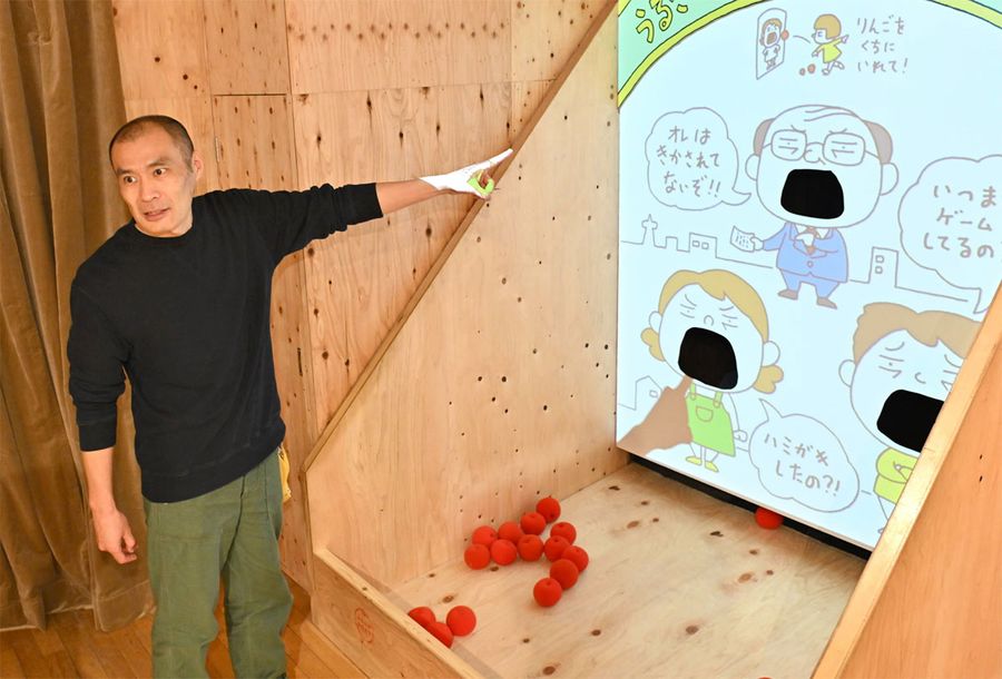 「子どもも遊べる空間を作った」と、うるさい大人の口にリンゴを投げ込む仕掛けを紹介するヨシタケシンスケさん(高知市の県立美術館=河本真澄撮影)