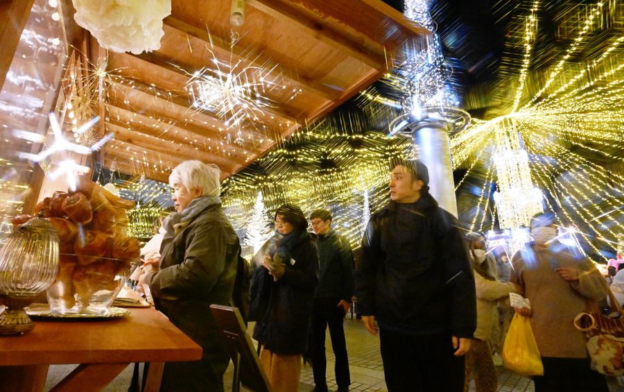 ステージで奏でられるクリスマスソングを聞きながら散策を楽しむ来場者たち