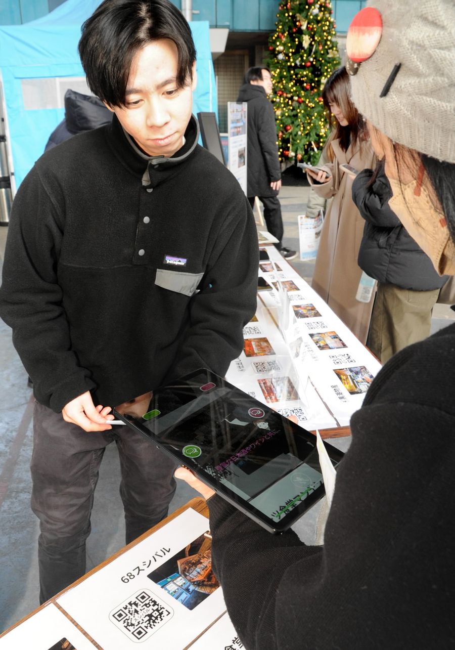 アバターを使ったアプリを紹介する高知工科大生（高知市帯屋町２丁目のひろめ市場）