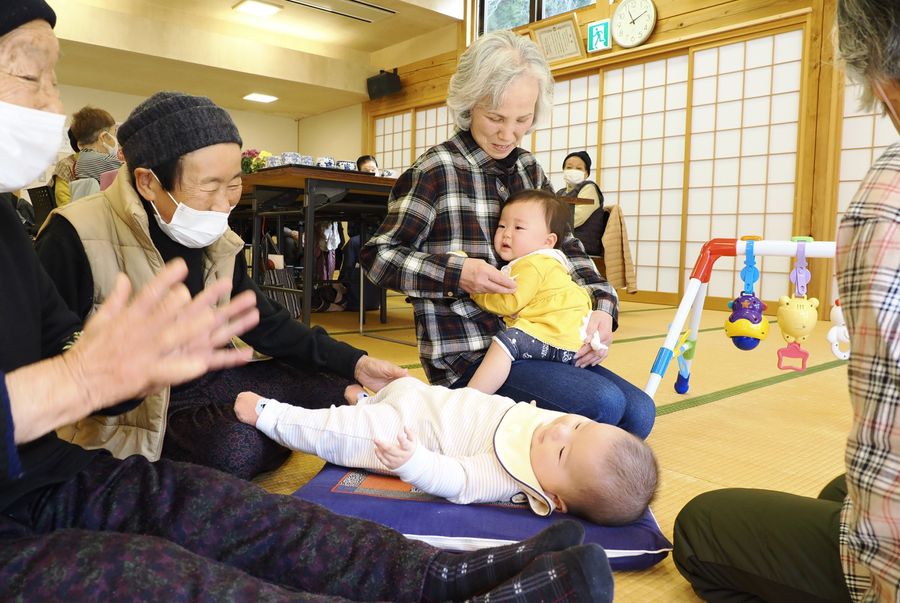 高齢者サロンにやって来た赤ちゃんたちのお守りをするお年寄り。お母さんの姿が見えなくなり、泣き顔の子も（梼原町六丁の集落活動センター四万川）
