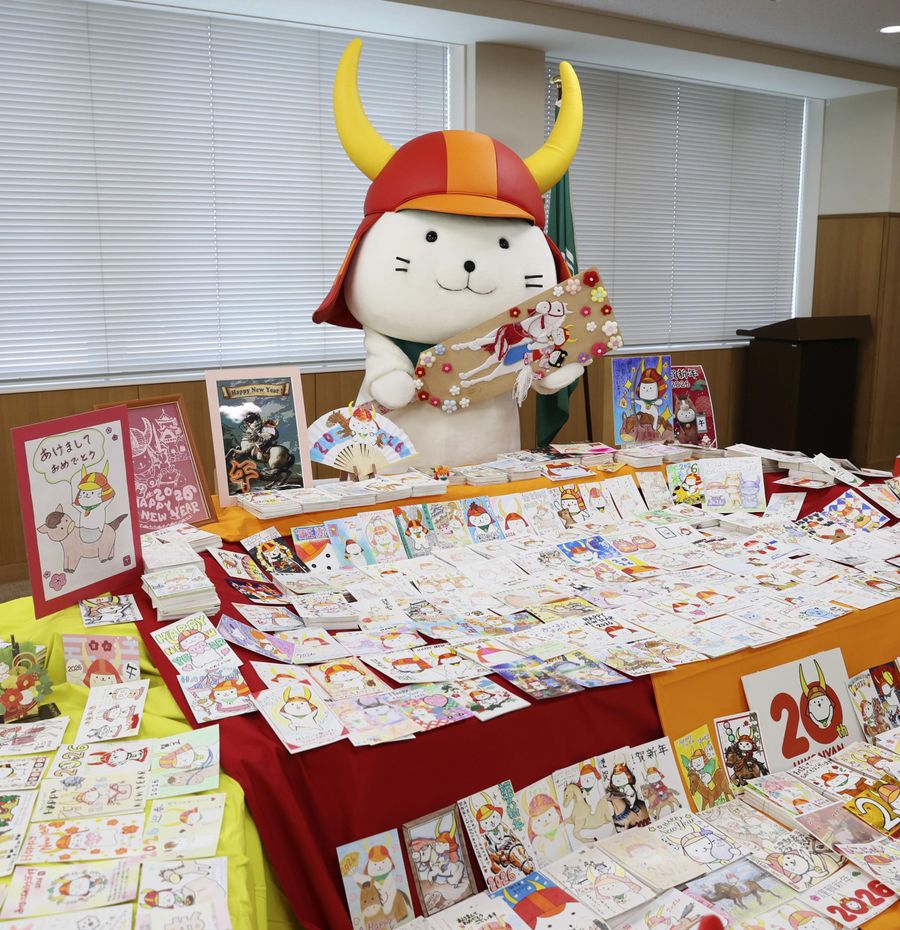 届いた年賀状を前に羽子板を持ってよろこぶひこにゃん（１月７日、滋賀県彦根市役所）