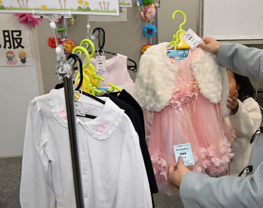 会場にはスーツやアンサンブルなど約５０着が並んだ。服を手に取った親子連れらからは「これ、かわいい！」などの声が聞かれた（高知市の総合あんしんセンター）