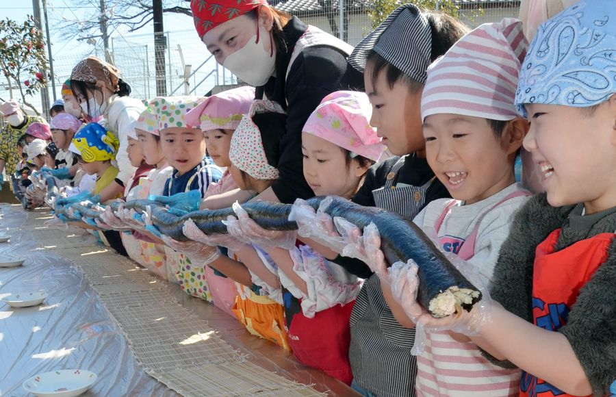 作った恵方巻きを持ち上げる園児ら（高知市のもみのき幼稚園）