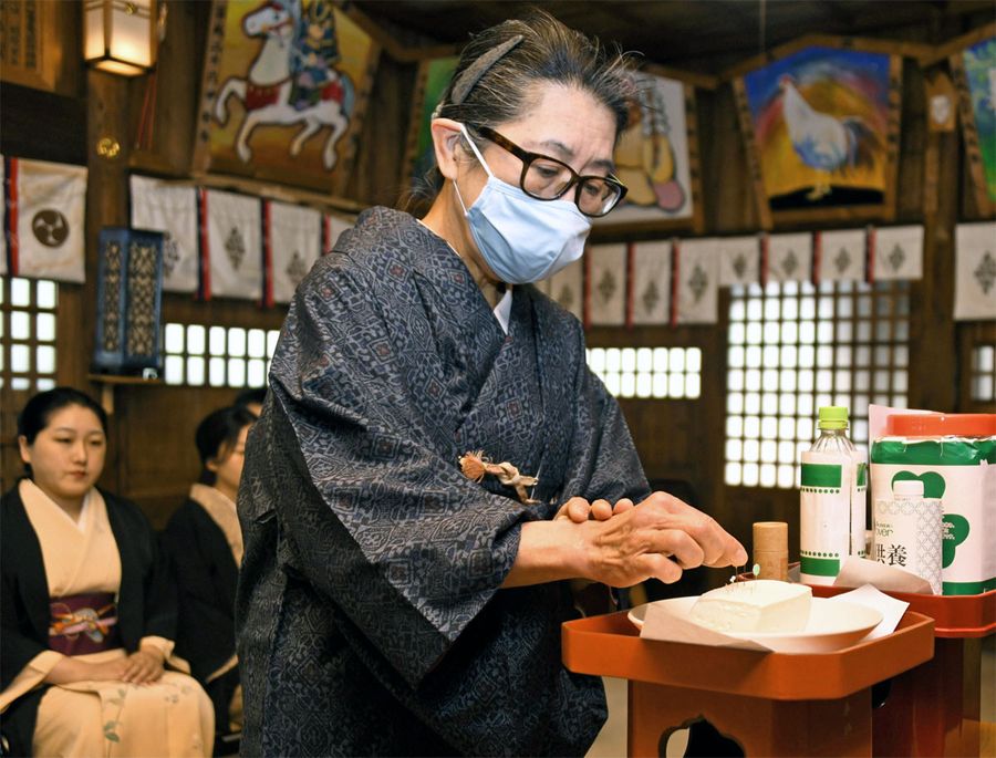 役目を終えた針を豆腐に刺す参列者(高知市の高知八幡宮)