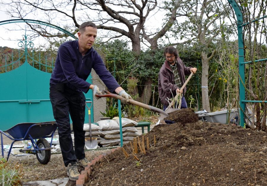 北川村の庭師から土壌改良について学ぶラファエル・メトルさん（左）＝北川村野友甲のモネの庭