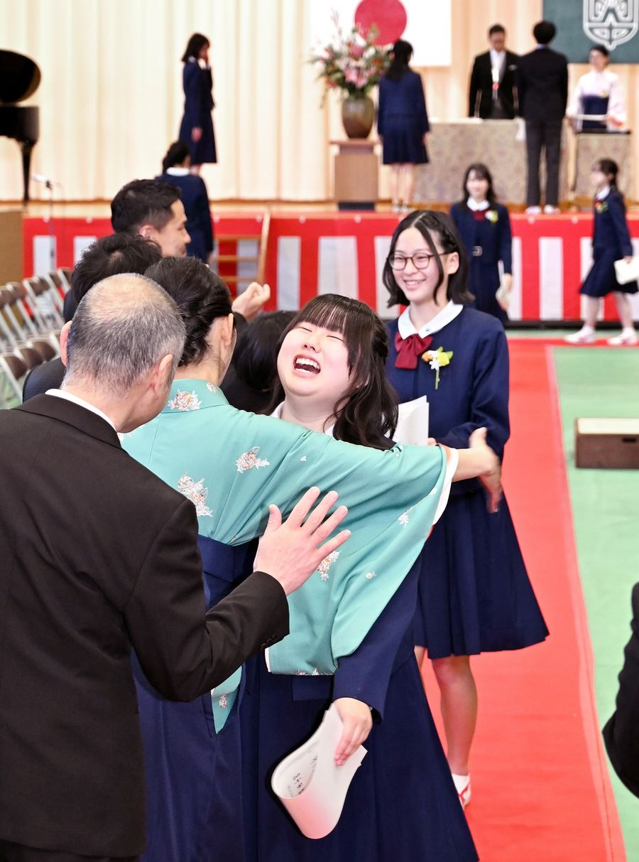 式を終えて退場する途中、担任らとハグする卒業生ら（高知市口細山の旭中学校＝森本敦士撮影）