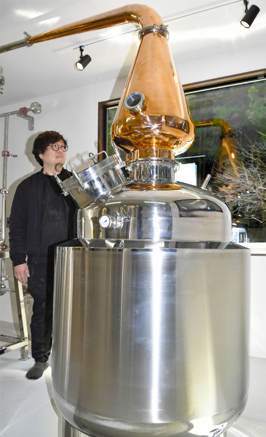 伏流水を使ってジンとウイスキーを製造する蒸留機と山崎祐大さん（仁淀川町竹ノ谷の仁淀川蒸溜所）