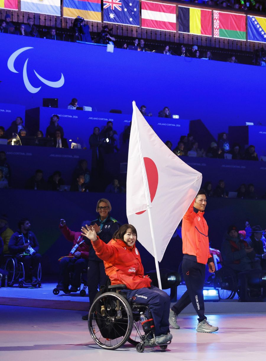 ミラノ・コルティナ冬季パラリンピックの閉会式で入場する日本選手団の旗手の小川亜希選手(左)と小須田潤太選手=3月15日、イタリア・コルティナダンペッツォ(共同)
