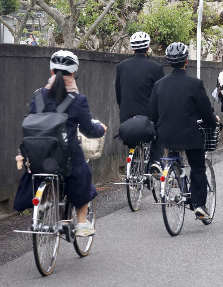 ヘルメットをかぶって自転車で登校する高校生＝２０２３年１２月、愛媛県内