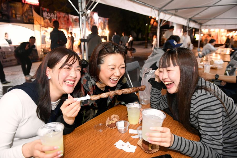 サワーを片手に牛串を頬張る女性グループ（高知市帯屋町１丁目の中央公園）